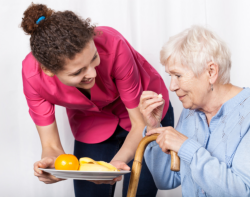caregiver feeding elderly with fruits